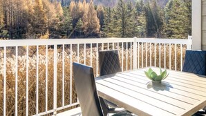 Eine Holzterrasse mit Tisch und Stühlen mit Blick auf ein bewaldetes Gebiet.