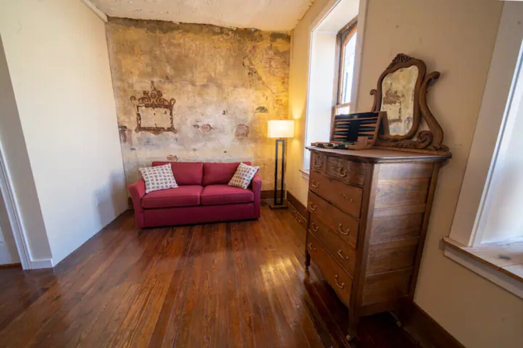 Ein Zimmer mit einem roten Sofa, einem Holzkapfen und einer Lampe.