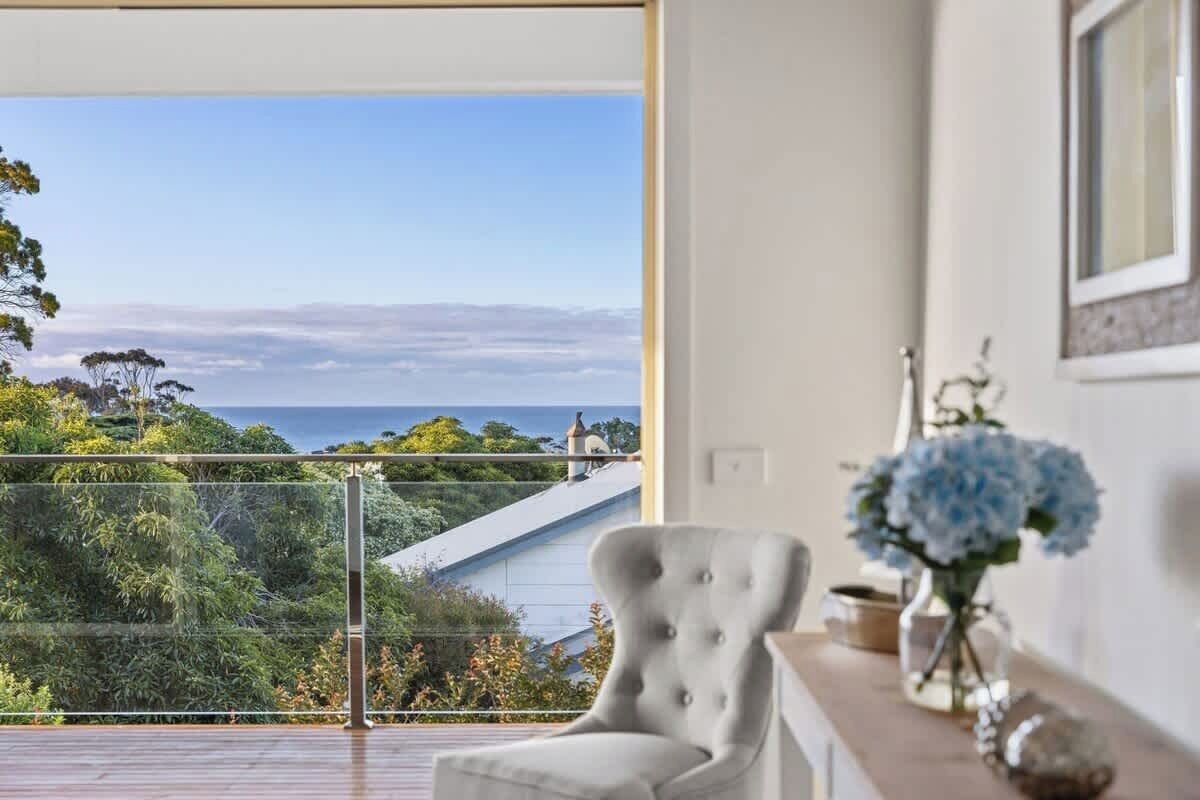 A room with a large window offering a view of a coastal landscape.