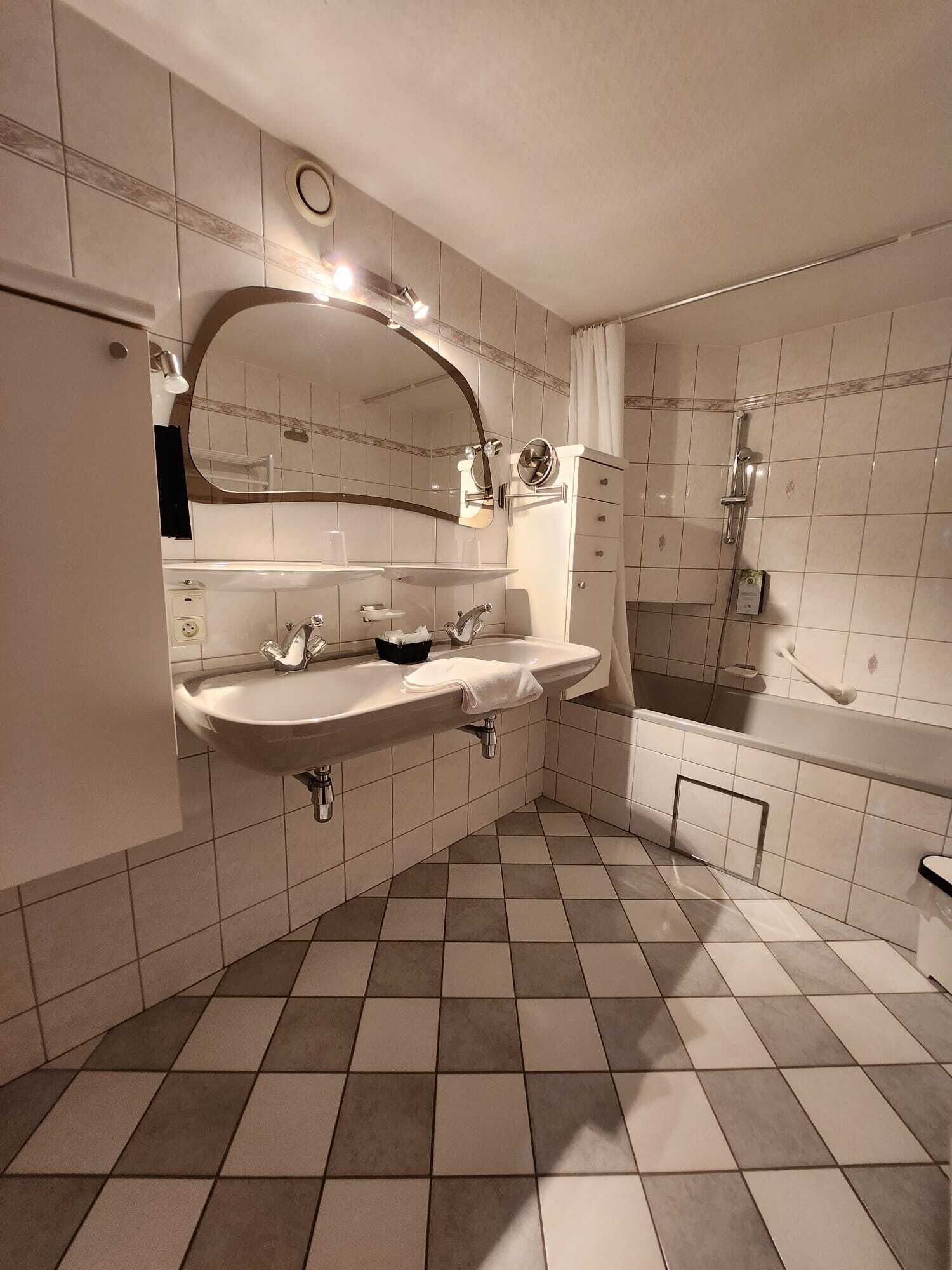 Ein Badezimmer mit einem großen Waschbecken, einem Spiegel und einer Dusche.