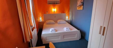 Ein Hotelzimmer mit Bett, Schreibtisch, Stuhl und Kleiderschrank.