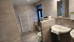 A modern bathroom with a large mirror, two sinks, and a toilet. - Pitlane Lodge (Stavelot)