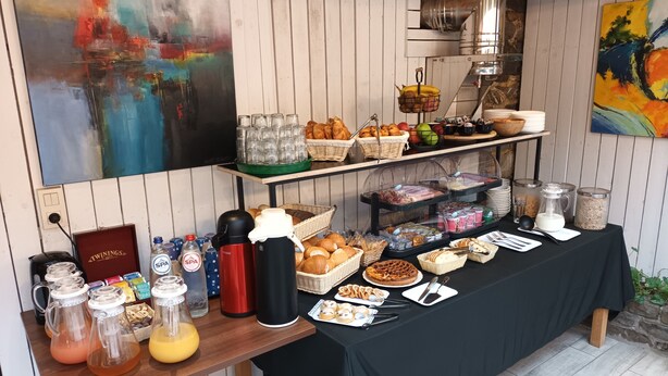 A buffet table with various food items, beverages, and condiments. - Pitlane Lodge (Stavelot)