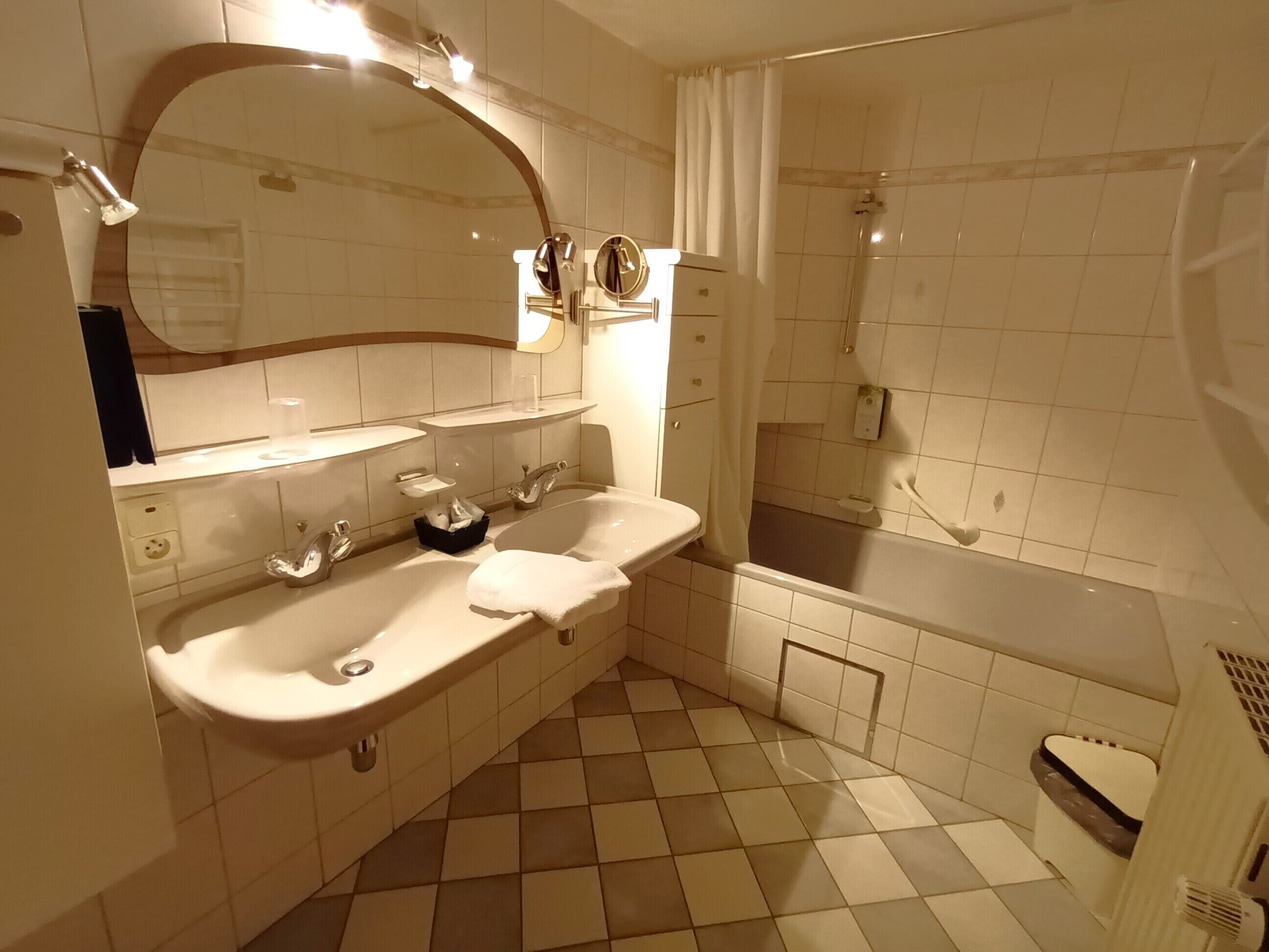 A bathroom with two sinks, a large mirror, a shower, and a tiled floor.