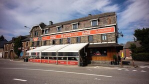 A building with a Coca-Cola sign, a restaurant, and a sign for a pizza place. - Pitlane Lodge (Stavelot)