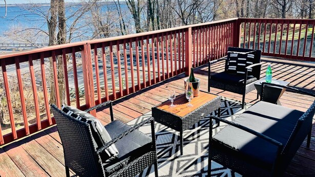 Una terraza con mobiliario exterior, vista al lago y barandilla de madera.