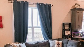 Una sala de estar con un sofá modular, un reposapiés a juego y una alfombra estampada.