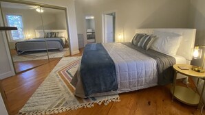 A bedroom with a bed, a bedside table, a mirror, and a ceiling fan. - Vintage Cottage less than 3 mi from Duke Hospital (Durham)