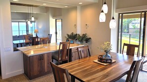 Une cuisine moderne avec un îlot central, une table à manger en bois et des chaises. Des luminaires suspendus sont placés au-dessus de l’îlot et de la table.