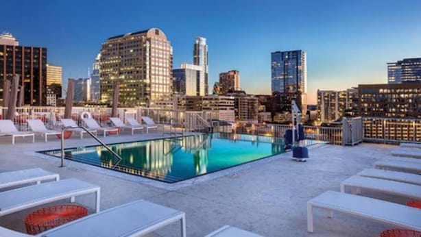 Un espace piscine aménagé sur le toit, avec des chaises longues et une vue sur le panorama urbain.