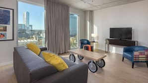 Un salon moderne avec un canapé, des fauteuils, un téléviseur et une table.