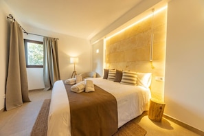 Una habitación de hotel moderna con una cama grande, una lámpara de noche y vistas al exterior.