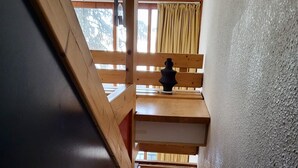 A wooden staircase leading to a loft bedroom with a blue sofa and a decorative vase. - Apartment Mezzanine Perriand Arcs 1800 Valley View (Les Arcs 1800)
