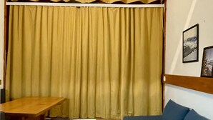 A room with a wooden table, blue stools, a blue sofa, a wooden floor, and a large curtain. - Apartment Mezzanine Perriand Arcs 1800 Valley View (Les Arcs 1800)