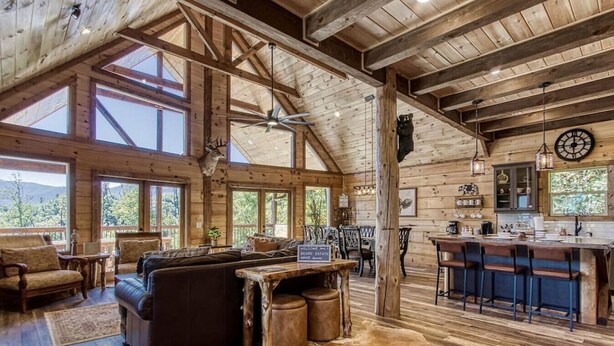 A rustic cabin interior with a large wooden ceiling, a bar area, and a seating area with a sofa and chairs. - Huge Mountain LOG Cabin with Amazing Views (Gatlinburg)