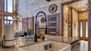 Une cuisine spacieuse dotée d’un grand plan de travail en granit, d’un évier encastré et d’un intérieur en bois.