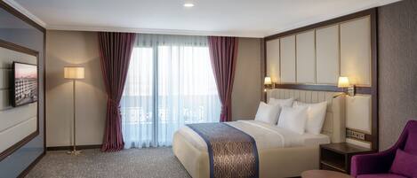 Une chambre d’hôtel avec un grand lit, un bureau, une chaise, une télévision et une vue sur la ville par la fenêtre.