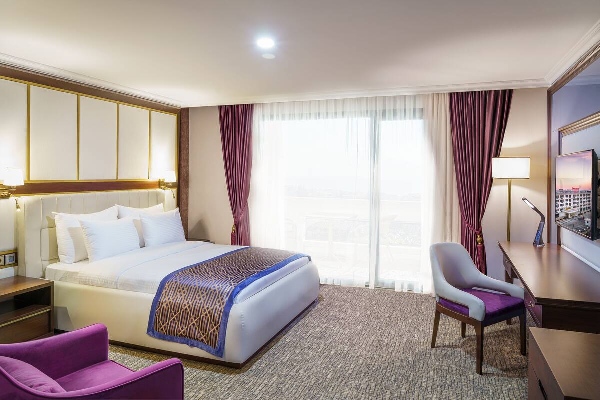 Een hotelkamer met een groot bed, een bureau, een stoel en een televisie.