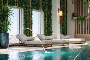 An indoor pool area with lounge chairs, a large potted plant, and vertical greenery on the walls. - Ramada By Wyndham Riyadh King Fahd Road (Riyadh)