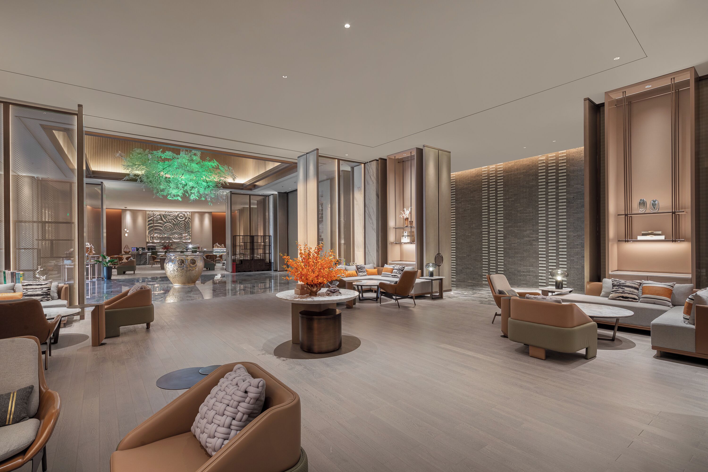 A spacious lobby with a central seating area, a large vase with orange flowers, and a modern interior design.