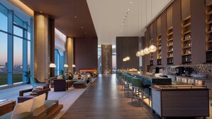 A modern hotel lobby with a long reception desk, bar area, seating, and large windows offering city views. - Wyndham Shanxi Xiaohe Xincheng (Taiyuan)