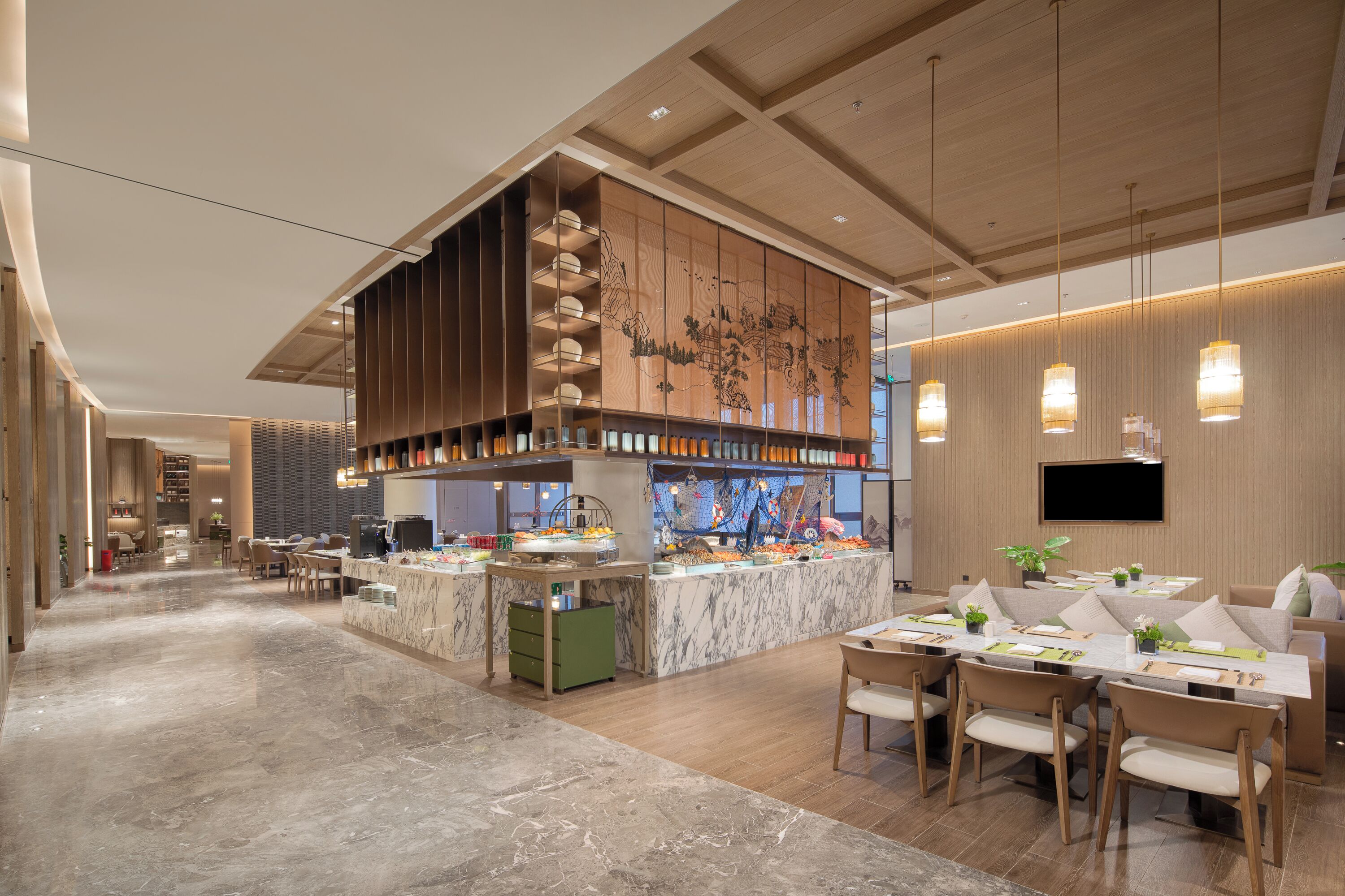 Un moderno vestíbulo de hotel con un mostrador de recepción de mármol, una zona de bar central y un espacio de estar con mesas y sillas.