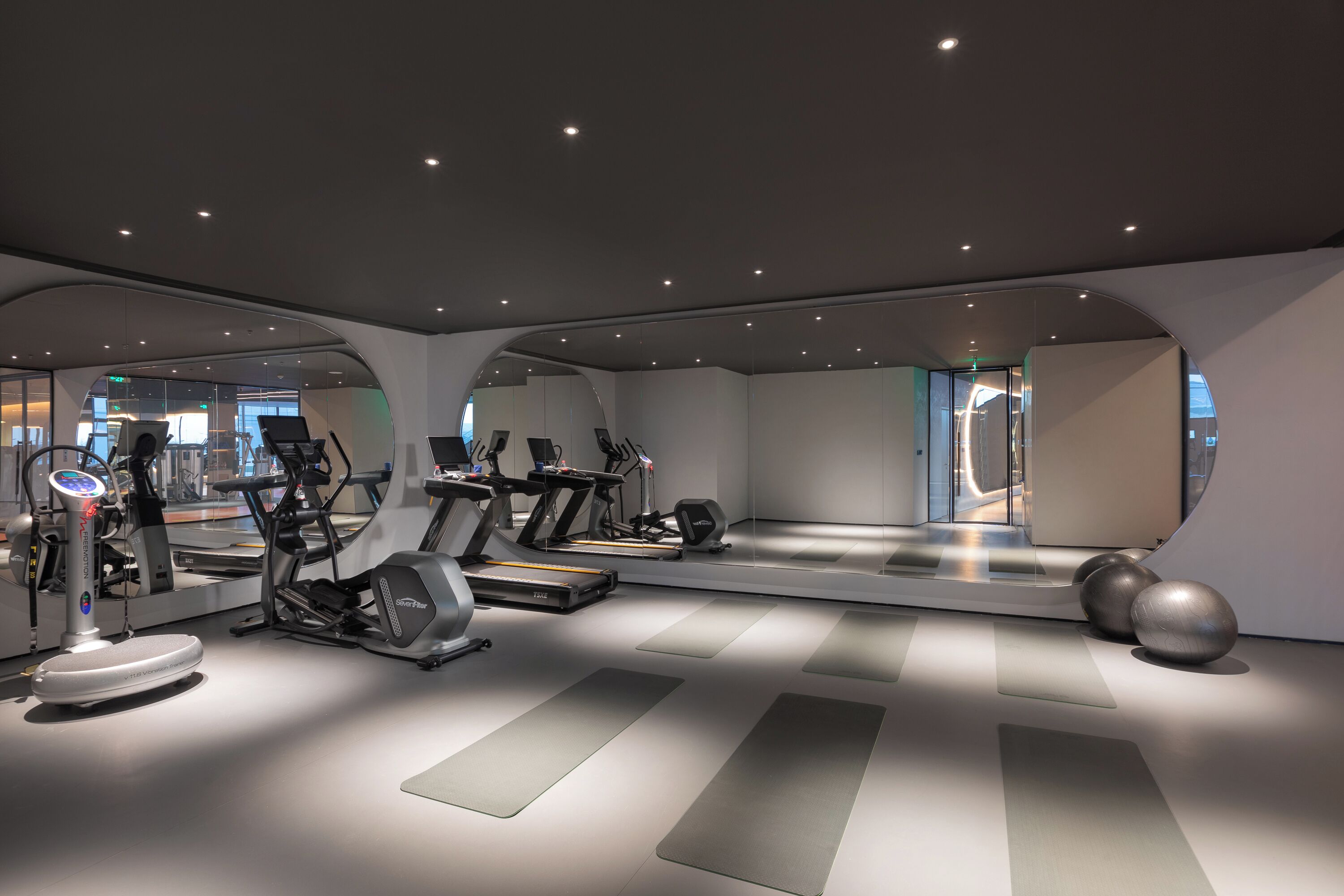 A modern gym with exercise equipment, a large mirror, and a clean, minimalist design.