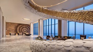 A spacious lobby with a unique ceiling design, large windows offering a city view, and modern seating arrangements. - Wyndham Shanxi Xiaohe Xincheng (Taiyuan)