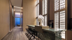 A modern kitchen with a marble countertop, black bar stools, and a decorative bust. - Wyndham Shanxi Xiaohe Xincheng (Taiyuan)