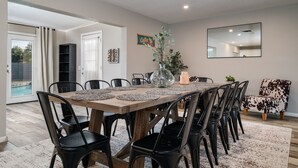 Un coin repas avec une table en bois, des chaises noires et un vase en verre contenant des plantes.