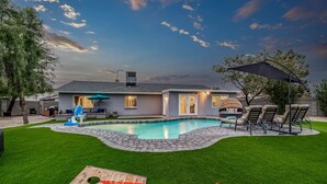 Une maison moderne dotée d’une piscine, d’un patio avec mobilier d’extérieur et d’une pelouse bien entretenue.