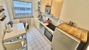 Een functionele keuken met een eettafel, een magnetron, een oven en een koelkast.