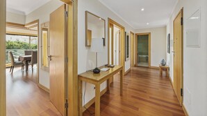Ein modernes Hotelzimmer mit Holzboden, einem Essbereich mit Tisch und Stühlen sowie einem Balkon mit Blick auf Grünflächen.