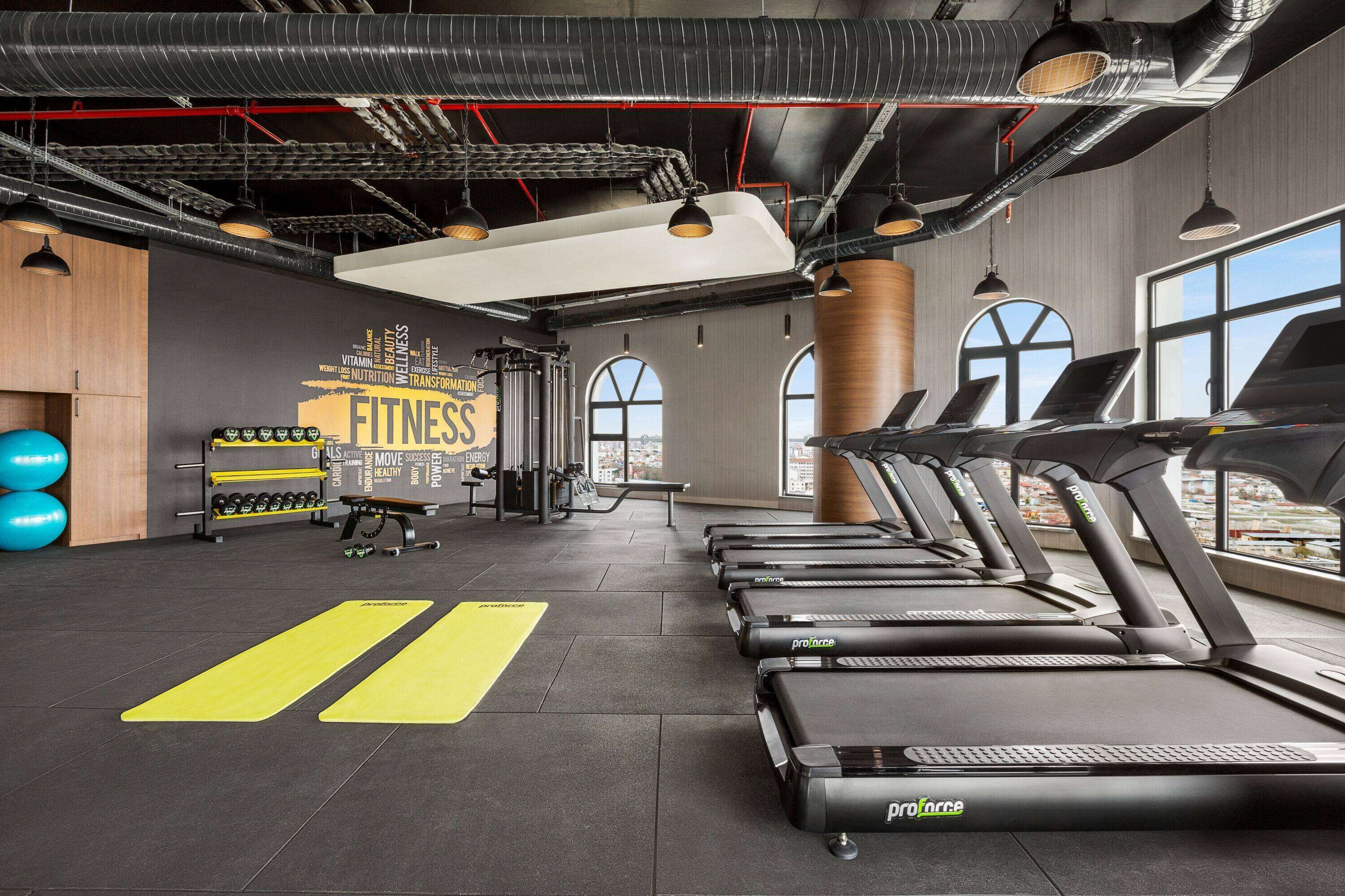 Un gimnasio con cintas de correr, pesas y pelotas de ejercicio.