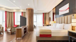Een moderne hotelkamer met een groot bed, een flatscreen televisie, een bureau en een zithoek.