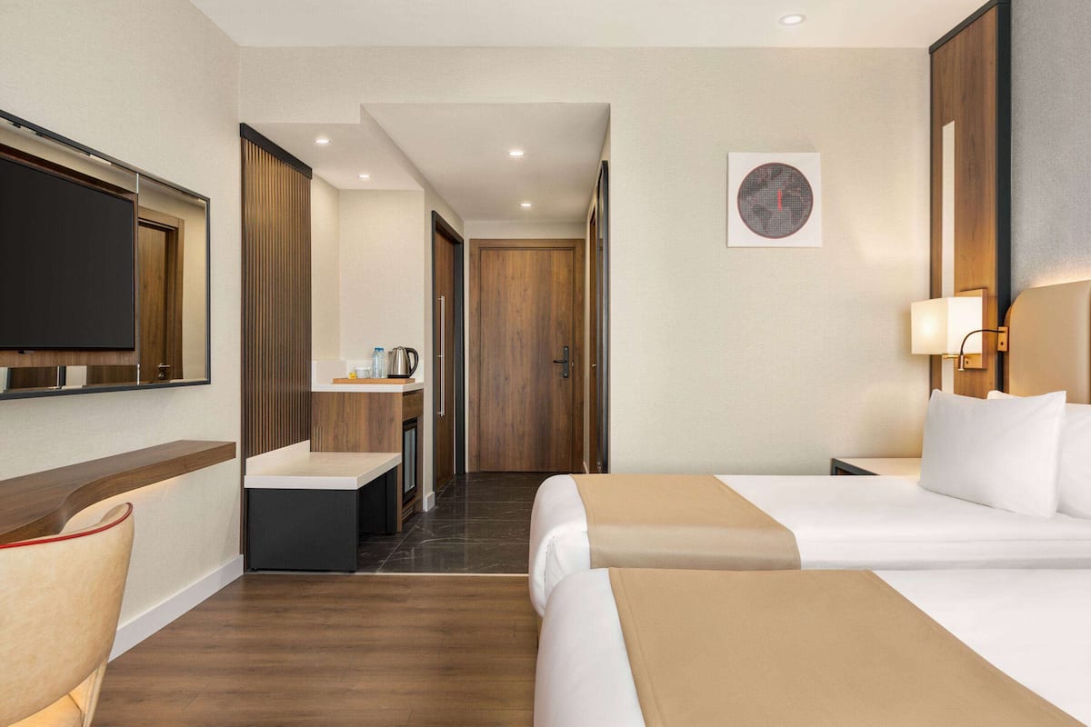 A hotel room with a bed, a desk with a chair, a television, and a coffee machine.