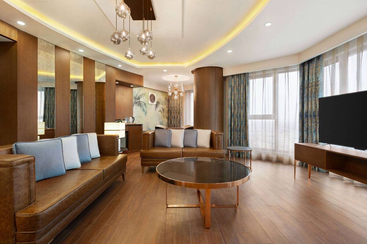 A spacious living area with a large sofa, a round coffee table, and a flat-screen TV.