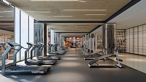 Un gimnasio moderno con cintas de correr, máquinas de pesas y un espejo grande.