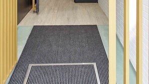 Ein modernes Interieur mit einer Treppe, die zu einer oberen Ebene führt, einer Tür mit Griff und einem gemusterten Teppich.