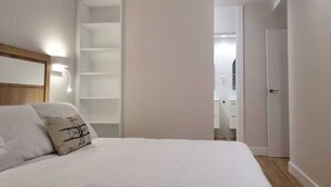 Ein Schlafzimmer mit einem Bett, einer Nachttischlampe, einem Kleiderschrank und einer Tür zu einem Badezimmer.