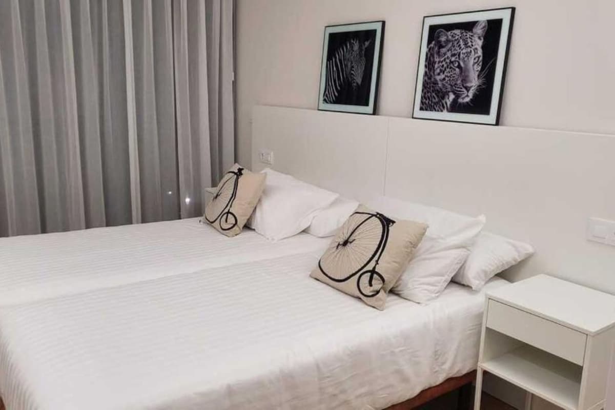 Ein Hotelzimmer mit einem Bett, zwei Kissen, einem Nachttisch und zwei gerahmten Bildern an der Wand.