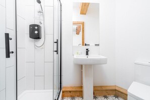 A modern bathroom with a glass shower enclosure, a white sink, and a wooden-framed mirror.