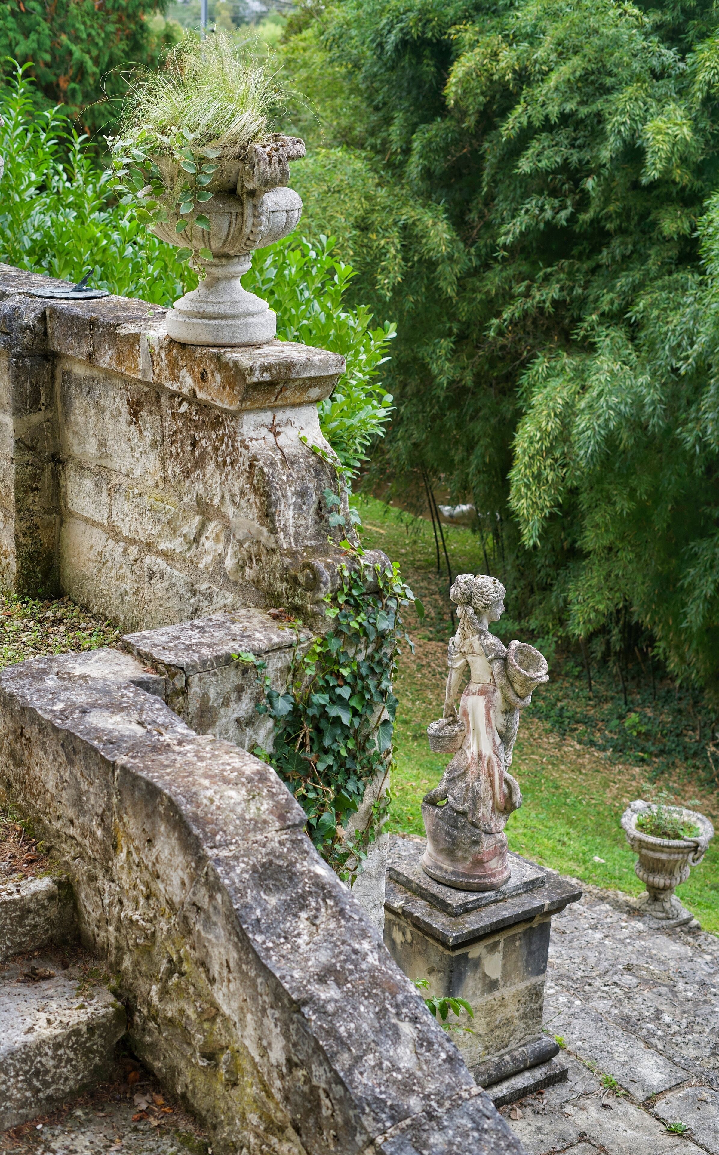 A stone structure with a statue and a decorative urn.