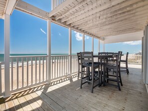 A covered outdoor area with a wooden deck, white railings, and a table with chairs.