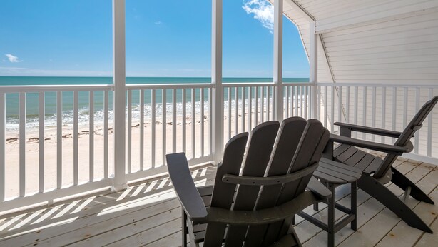 A covered deck with two Adirondack chairs facing a beach. - Just Beachy: Beachfront, Private pool, Pet Freindly (St. George Island)