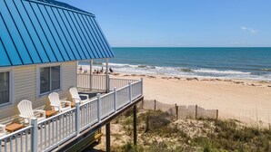 A beach house with a blue roof, white deck chairs, and a wooden fence. - Just Beachy: Beachfront, Private pool, Pet Freindly (St. George Island)