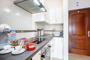 Une cuisine moderne avec des meubles blancs, un plan de travail noir et une porte en bois.