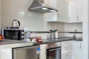 A modern kitchen with stainless steel appliances, white cabinets, and a tiled backsplash.