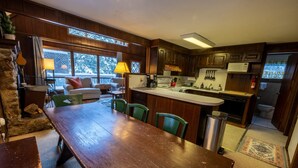 A cozy kitchen with wooden cabinets, a dining table, and a stone fireplace. - Spacious Chalet, Skiing 5 Minutes to Jay Peak, Vermont! (Montgomery)