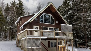 A wooden cabin with a balcony, surrounded by snow-covered trees. - Spacious Chalet, Skiing 5 Minutes to Jay Peak, Vermont! (Montgomery)